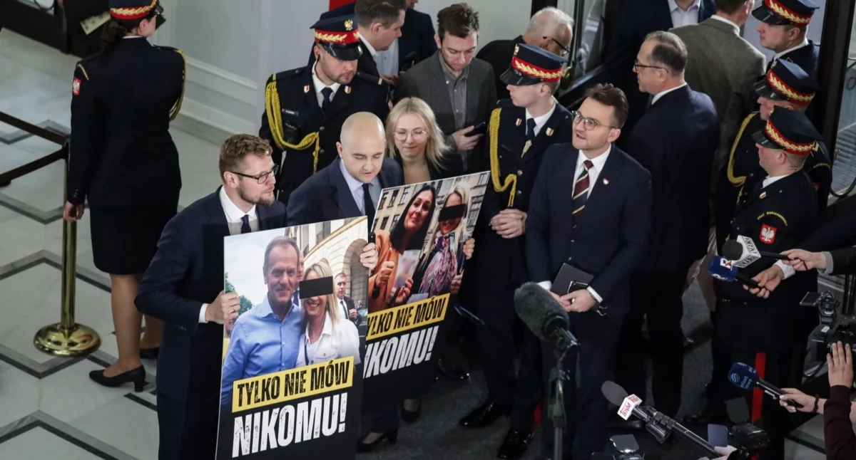 Wykluczeni przez marszałka Sejmu z posiedzenia izby posłowie PiS Michał Woś (L) i Dariusz Matecki (2L) prezentują na korytarzu Sejmu banery ze zdjęciami premiera Donalda Tuska i wicemarszałek Sejmu Moniki Wielichowskiej z byłą działaczką PO w Kłodzku Kamilą L. Fot. PAP/Tomasz Gzell